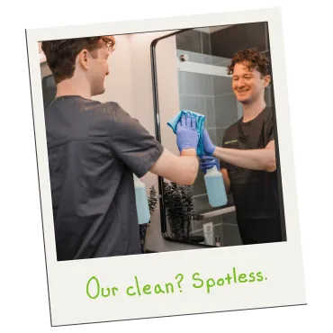 Merry Maids of York professional housekeeper cleaning a bathroom mirror with a microfiber cloth and spray bottle
